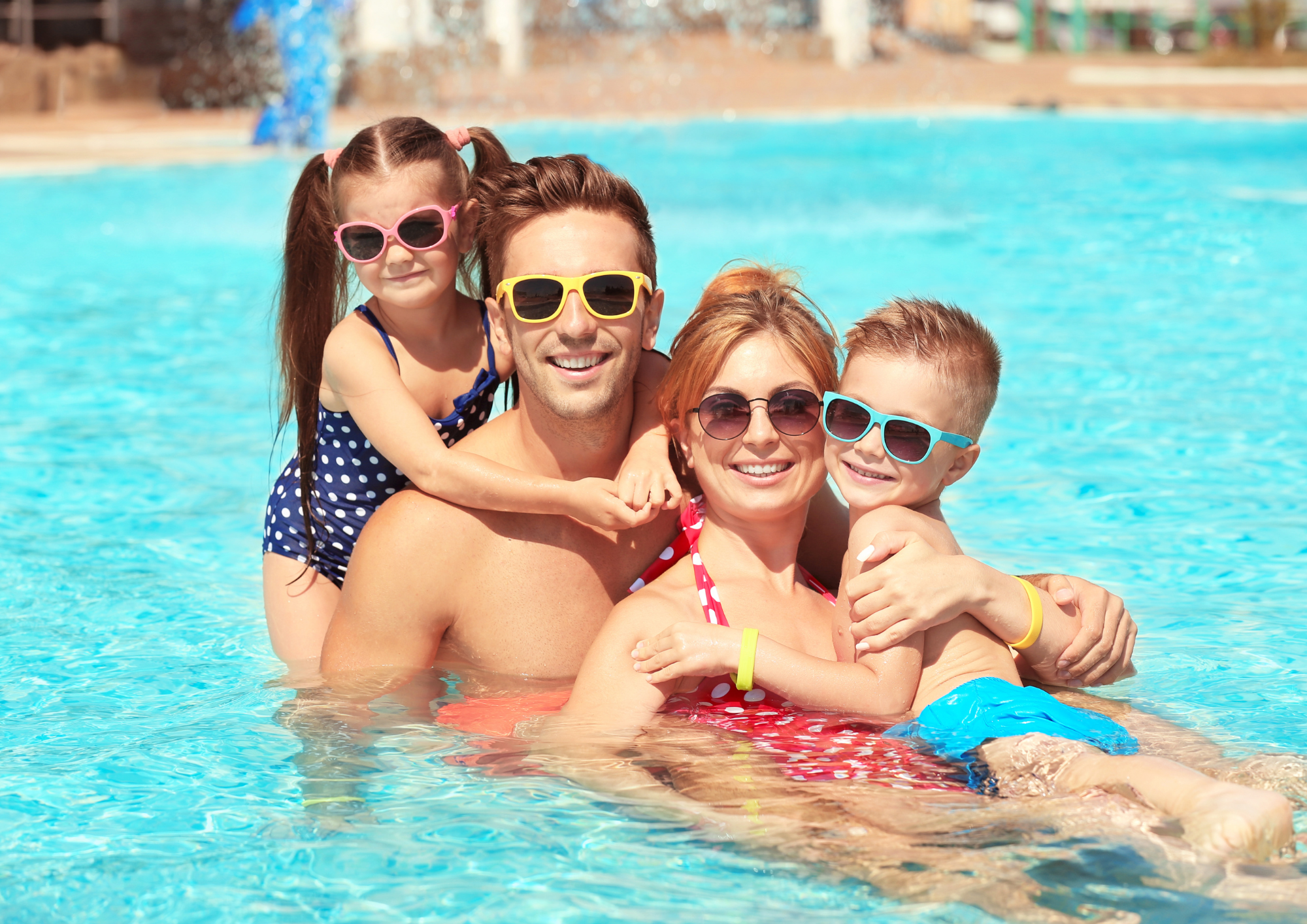 Niños con sus padres con seguridad en una piscina