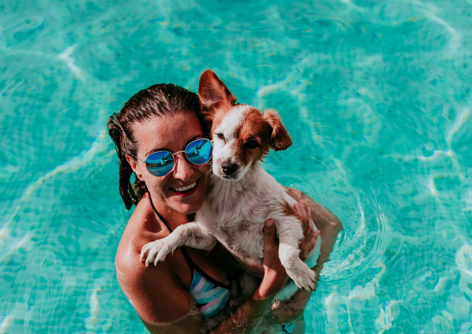 Mujer con su mascota en la piscina pasándolo bien