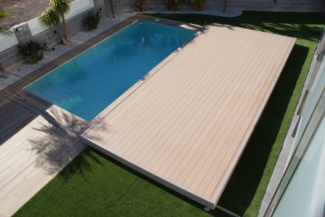 Piscina de obra de una casa donde se puede apreciar la tarima deslizante y motorizada que tiene la piscina para proteger el interior de la piscina
