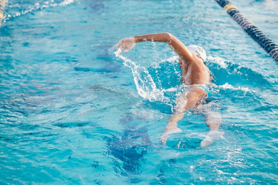 Hombre experto en natación que se encuentra nadando en una piscina entrenando y preparándose para su próxima competición de natación que tiene